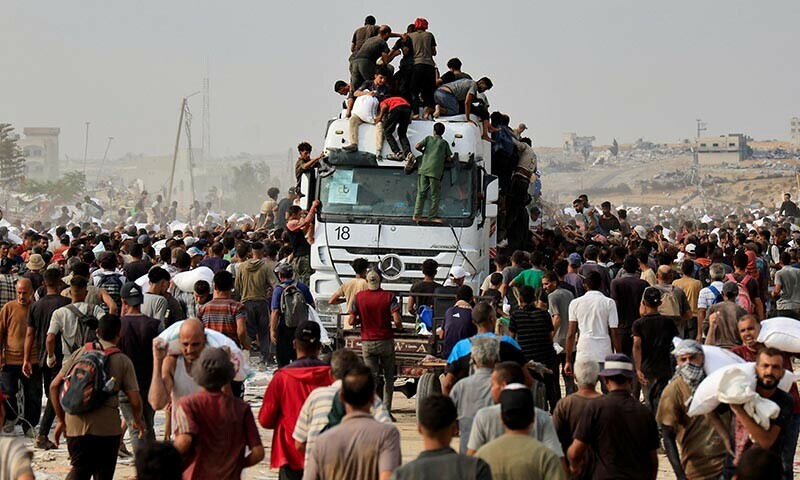Palestinians scramble to collect aid supplies from trucks that entered through Israel, in Khan Younis, southern Gaza Strip, August 12, 2025. &mdash; Reuters