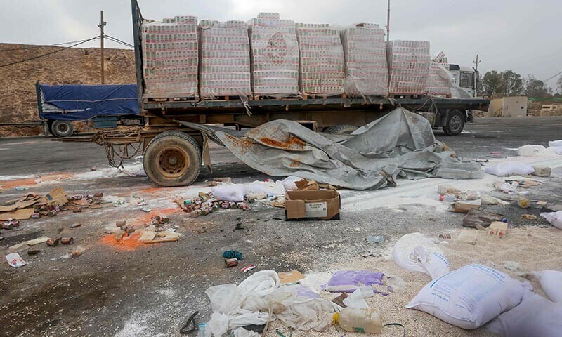 Damaged humanitarian aid for Palestinians in Gaza lies scattered on the ground next to broken-down trucks near the border with the Gaza Strip, close to the Kissufim crossing in southern Israel, on August 13, 2025. &mdash; AFP