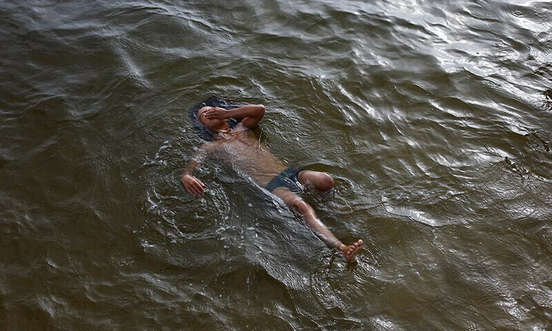 A displaced Palestinian child swims in the sea to cool off during summer heat in Gaza City, August 12, 2025. &mdash; Reuters