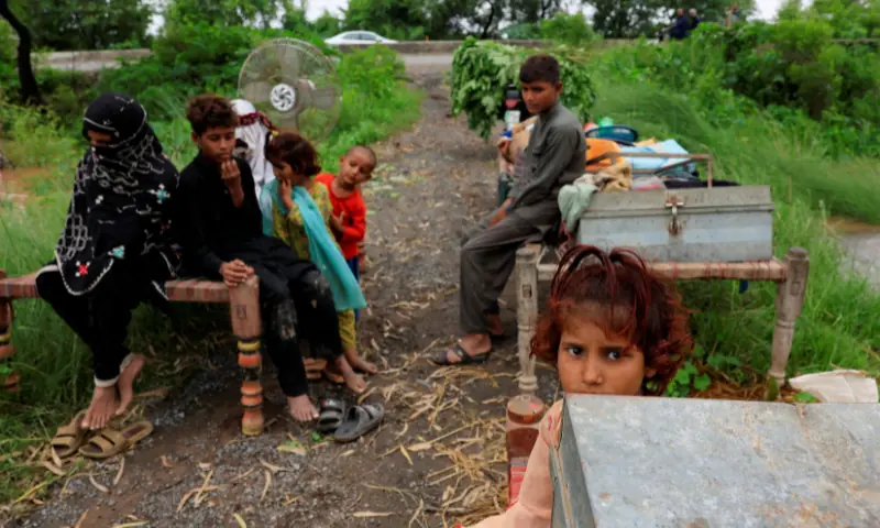 A family with their belongings takes refuge along a road near Chenab River, following the monsoon rains and rising water level in Punjab&rsquo;s Wazirabad, on August 27, 2025. &mdash; Reuters