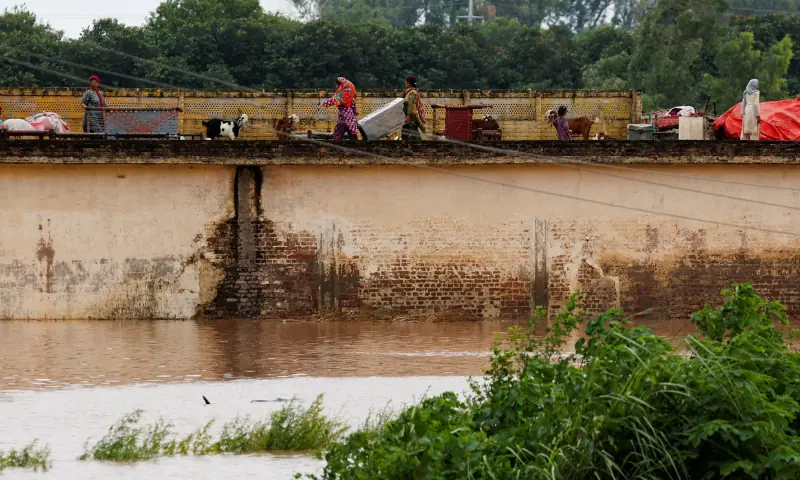 A family with their belongings takes refuge over a roof of their house near Chenab River, following the monsoon rains and rising water level in Punjab&rsquo;s Wazirabad, on August 27, 2025. &mdash; Reuters