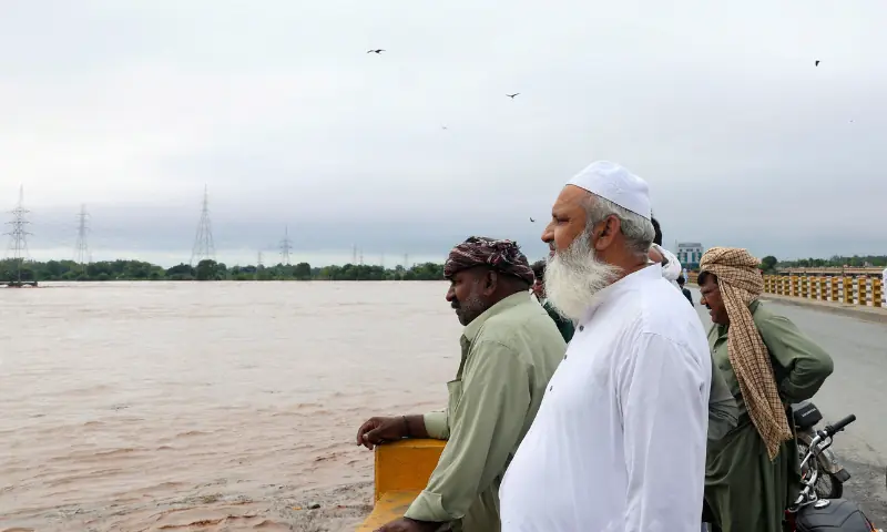 Men stand on a bridge over the Chenab River, following the monsoon rains and rising water level in Punjab&rsquo;s Wazirabad, on August 27, 2025. &mdash; Reuters