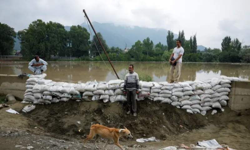 Residents place sandbags to prevent the berm they built from being washed away as water levels rise in the Jhelum River following heavy rain, in Srinagar, Indian-occupid Kashmir, on August 27. — Reuters