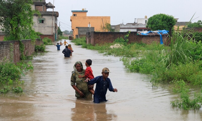 Residents wade through a flooded street, following monsoon rains and rising water levels in Sialkot, August 27. — Reuters