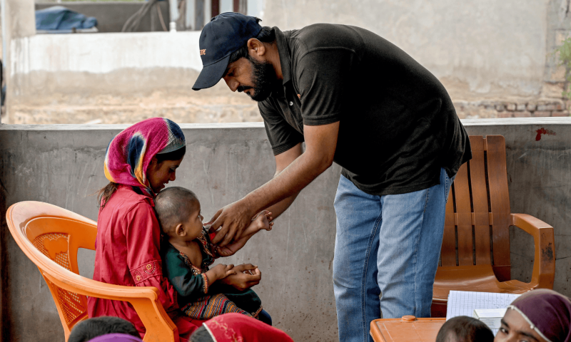 This photograph taken on July 29, 2025 shows a health worker (R) checking the health of a child during a UNICEF nutrition programme at Fateh Muhammad Soomro village in the Sujawal district of Sindh. — AFP