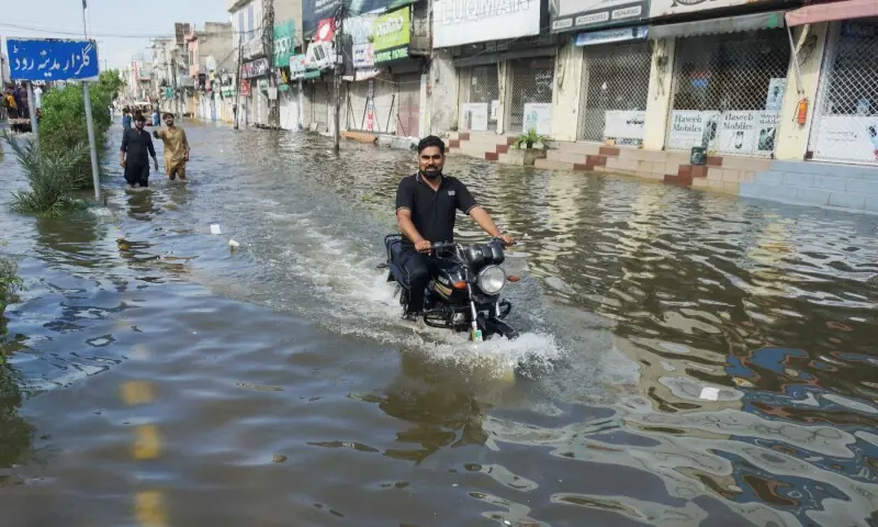  A man rides a motorbike through a flooded road, with closed shops in the background, following monsoon rains and rising water levels of the Chenab River, in Gujrat, Punjab on Sept 5, 2025. &mdash; Reuters/Stringer 