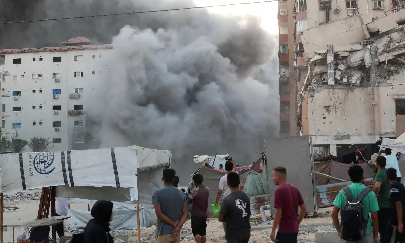 Palestinians watch as smoke rises while a residential building collapses after an Israeli air strike, in Gaza City on Sept 7, 2025. —Reuters/Mahmoud Issa