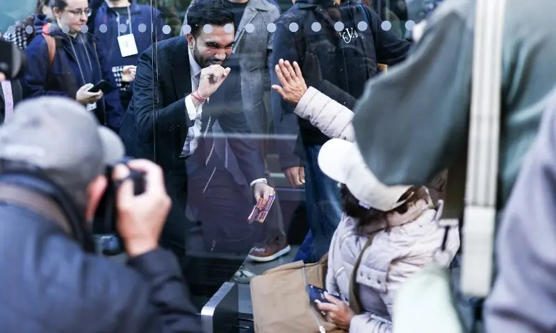 Democratic socialist candidate Zohran Mamdani greets a woman at a bus stop in the Manhattan borough of New York City during early voting for the upcoming mayoral election on October 27. —AFP