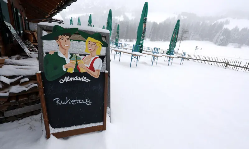 An advertising sign stands in front of a closed beer garden in the snow in Bad Hindelang, Germany on November 20. — AFP