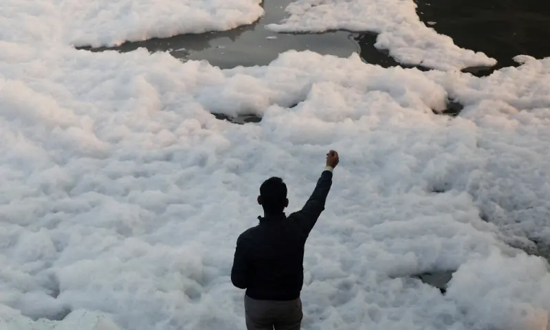 A fisherman uses a string to catch fish through foam on the polluted Yamuna river, on a smoggy morning amid ongoing air pollution in New Delhi, India, on November 21. — Reuters