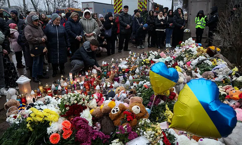 People stand at a makeshift memorial for the victims who were killed when a Russian missile hit an apartment building on Wednesday in Ternopil, Ukraine on November 21, 2025. — Reuters