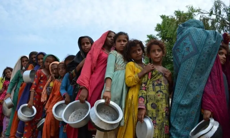 Pakistanis displaced by floods queue for food at a camp in Sehwan, Sindh Province, in 2022. — Husain Ali / AFP