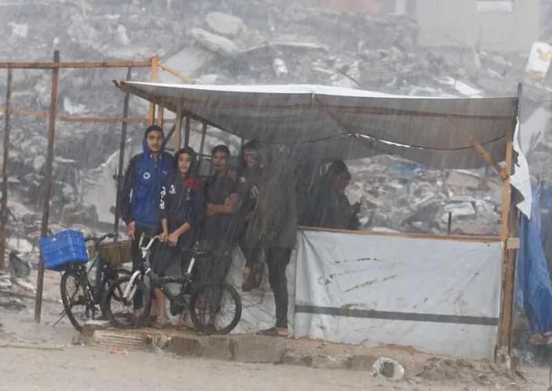 Displaced Palestinians shelter under a tent next to piles of rubble, during a rainy day in Gaza City, November 25. &mdash; Reuters