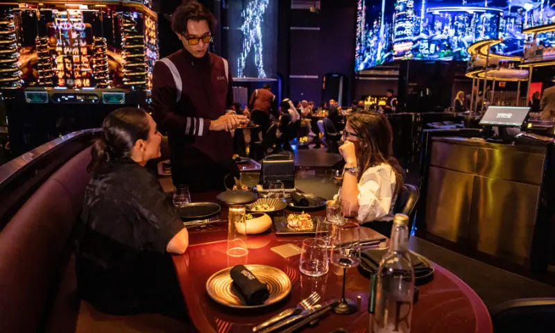 In this photo taken on November 12, 2025, a waiter interacts with customers at Woohoo, an AI-powered restaurant in Dubai. — AFP