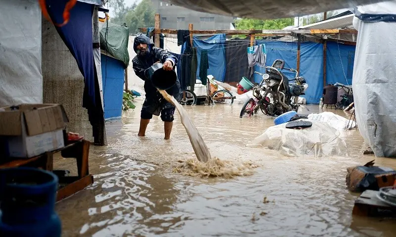 A displaced Palestinian man clears muddy water in a flooded tent camp on a rainy day in Nuseirat, central Gaza Strip, December 12, 2025. —Reuters