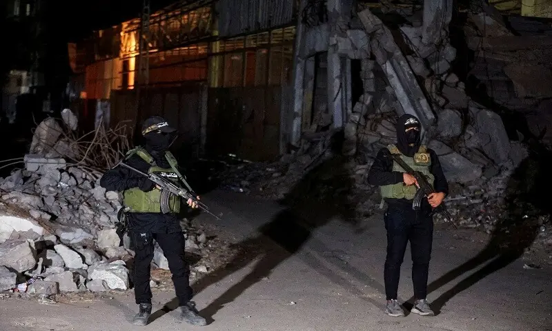 Hamas fighters stand guard as Red Cross vehicles transport the bodies of hostages who were held in Gaza. —Reuters