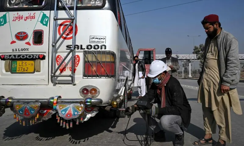 This picture taken on December 10, 2025, shows technician Waleed Ahmed (3R) examining a vehicle to test its emissions on road, on the outskirts of Islamabad.  &mdash; AFP