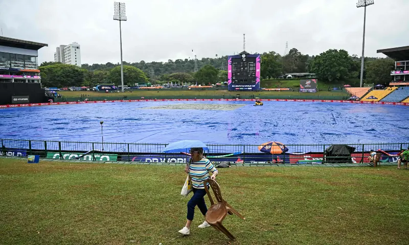  A cricket fan carrying an umbrella walks past the covered pitch as rain delays the start of the 2026 ICC Men&rsquo;s T20 Cricket World Cup group stage match between Zimbabwe and Ireland at Pallekele International Cricket Stadium in Kandy on Feb 17, 2026. &mdash; AFP 