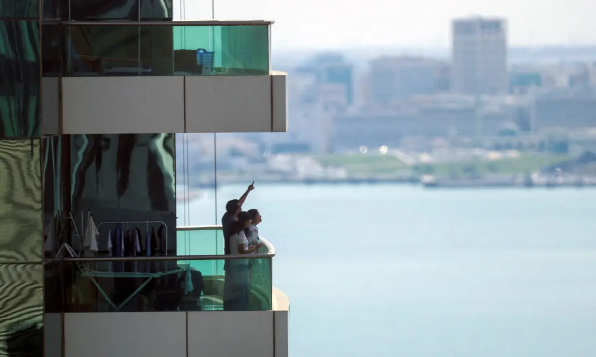 People watch from their balcony following explosions after the Qatar&rsquo;s defense ministry says it has downed missiles targeting the country, in Doha, Qatar on February 28, 2026. &mdash; Reuters