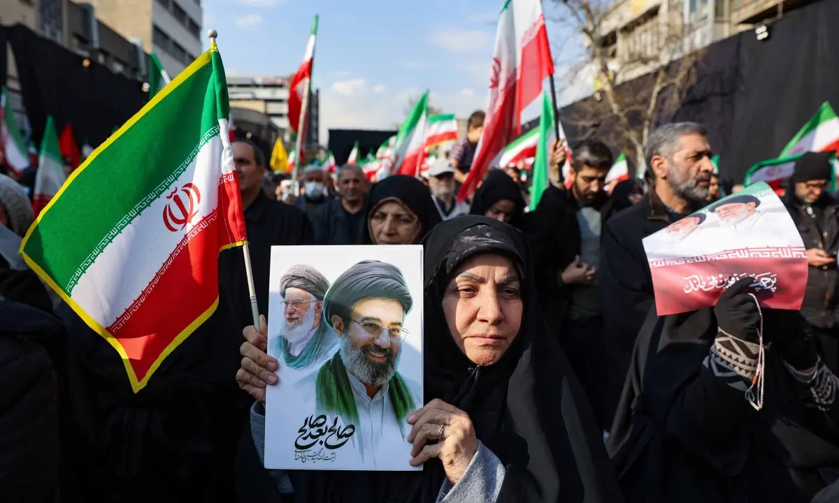 A woman holds a placard with an image of Iran&rsquo;s new Supreme Leader Ayatollah Mojtaba Khamenei, alongside late Iranian Supreme Leader Ayatollah Ali Khamenei in Tehran, Iran, March 9, 2026. &mdash; AFP