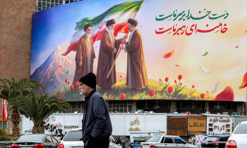 A man walks near a banner displayed at Valiasr Square in central Tehran on March 10, 2026. &mdash; AFP