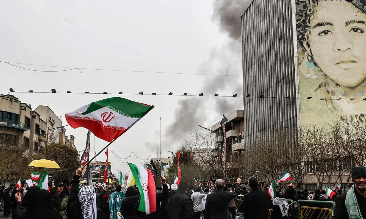 Black smoke rises after an airstrike as Iranians some holding up the national flag as they take part in the Al-Quds (Jerusalem) Day rally, in Tehran on March 13, 2026. &mdash; AFP