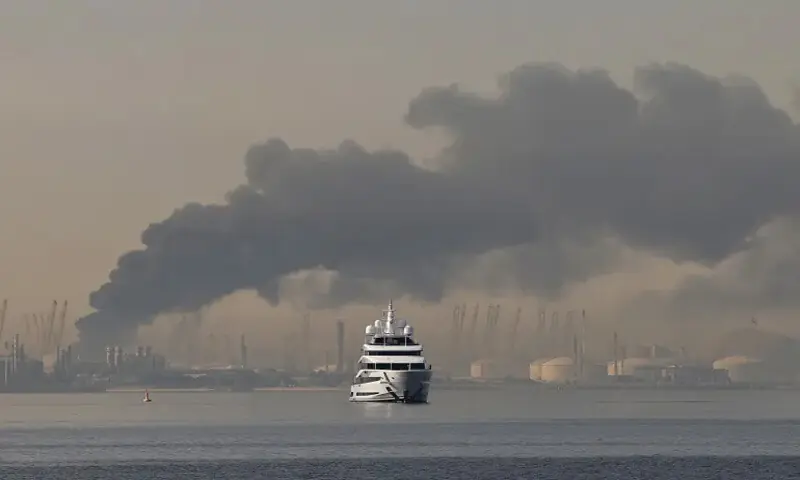 A yacht sails past a plume of smoke rising from the port of Jebel Ali after a reported Iranian attack on Dubai on March 1: Iran has adopted a calculated strategy of horizontal escalation that aims to broaden the conflict’s geographic and economic scope | Reuters