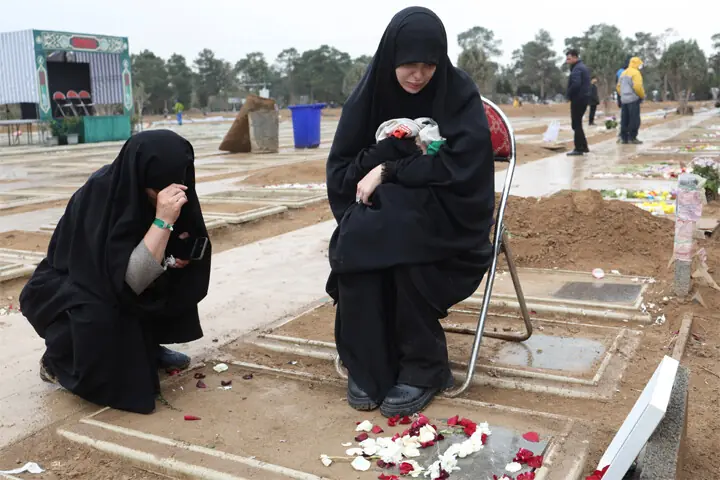 A woman sits with a relative beside her husband&rsquo;s grave at the Behesht-i-Zahra cemetery in Tehran.&mdash;Reuters