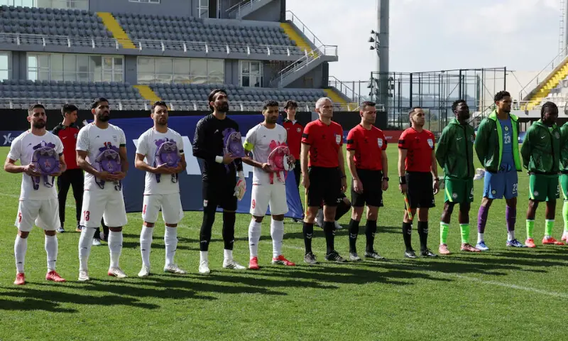 Iran players line up before the match as school bags are laid in memory of the victims of the girls school bombing in Minab, Iran, March 27, 2026. &mdash; Reuters