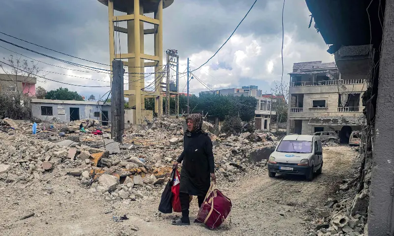 A woman walks with salvaged items from a destroyed building following overnight Israeli bombardment on the village of Maarake in southern Lebanon on April 7, 2026. — AFP