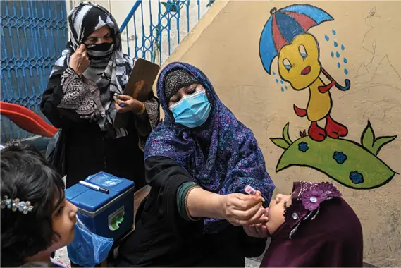  A healthcare worker administers drops to a child during a door-to-door poliovirus eradication campaign  in Lahore.&mdash;AFP 
