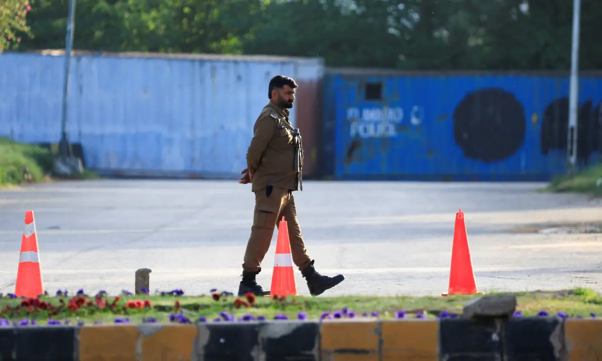 A police officer guards a road blocked with shipping containers, for security measures at D Chowk near the President&rsquo;s House as Pakistan prepares to host the United States and Iran for the second phase of peace talks in Islamabad on April 20, 2026. &mdash; Reuters