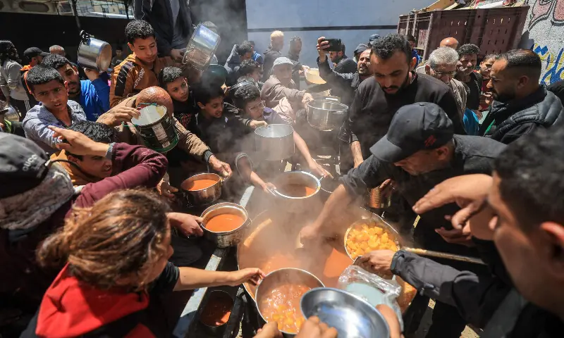Displaced Palestinians receive food from a charity kitchen at the Nuseirat refugee camp in the central Gaza Strip on April 22, 2026. — AFP