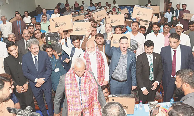  STUDENTS wave laptops to rejoice the gift at a ceremony in Shah Abdul Latif University, Khairpur, on Friday.&mdash;Dawn 