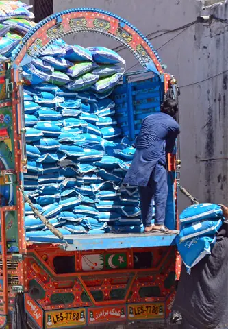   Labourers unload sacks from a truck at Ganjmandi area in Rawalpindi. The district administrations of the twin cities gave permission to all types of public and goods transport to enter the cities. &mdash; Online  