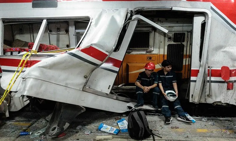 Workers sit at the site of a train collision as rescuers work to save five survivors trapped inside a carriage after a passenger train locomotive pierced through the rear car of a commuter train at Bekasi Timur station in Bekasi, West Java on April 28, 2026. &mdash; AFP