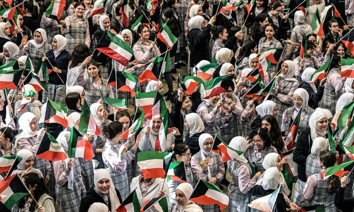 Secondary school students wave the Kuwaiti flag as they gather in the grounds of the Fajr al-Sabah School to attend in-person classes in Kuwait City on May 3, 2026. High school students resumed in-person classes after a suspension of more than two months following military strikes launched by the US and Israel against Iran that assassinated its supreme leader, triggering a war that spread across the Middle East and prompting the Kuwaiti Education Ministry to implement remote learning for students. &mdash;AFP
