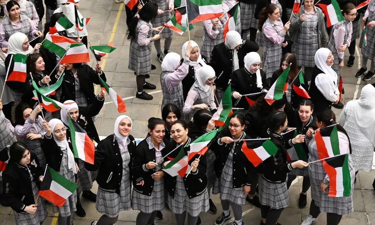 Secondary school students wave the Kuwaiti flag as they gather in the grounds of the Fajr al-Sabah School to attend in-person classes in Kuwait City on May 3, 2026. &mdash;AFP