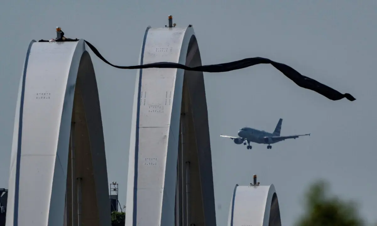 Anti-war protester Guido Reichstadter atop the Frederick Douglass Memorial Bridge, with an airplane flying in the background, in Washington, DC, US on May 5, 2026. &mdash;Reuters