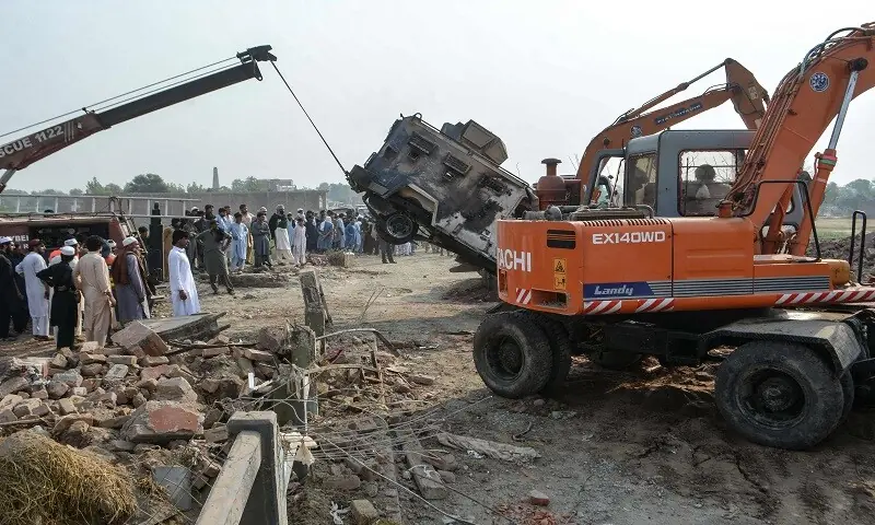 A crane removes a burned armored vehicle from a damaged police checkpost site following a car bombing attack by terrorists. — AFP