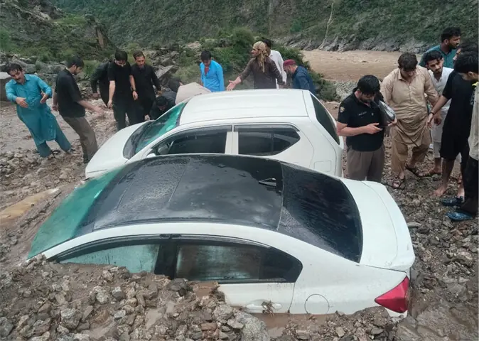  Villagers and tourists stand close to the vehicles stuck in the mudslide in Dubair area of Lower Kohistan on Tuesday. &mdash; Dawn 