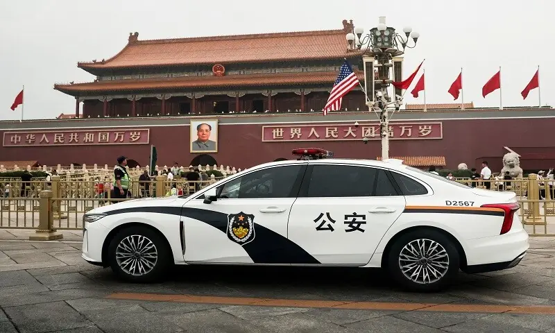 A police car drives past Tiananmen Gate with US and China’s national flags on a lighting pole during US President Donald Trump visit to China, in Beijing, China, May 15, 2026.