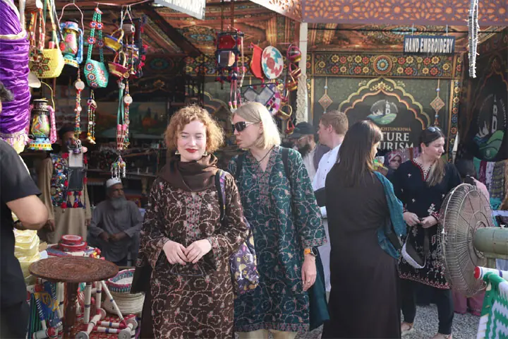  Artists stage &lsquo;Shehrag&rsquo; play at Nishtar Hall, Peshawar, on Sunday. (Right) Foreign tourists visit stalls at the Mela. &mdash; Dawn  