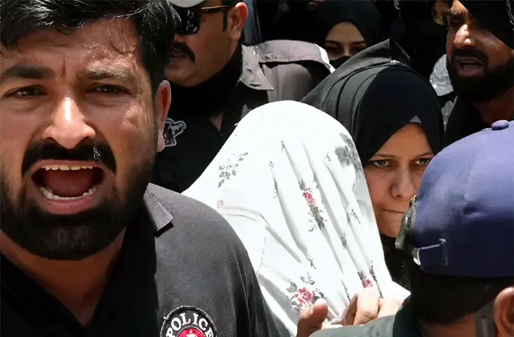  A policeman shouts at the media as others escort alleged cocaine dealer Anmol Pinky, who is covered with a chador, to the Judicial Complex inside Karachi Central Prison.&mdash;PPI 