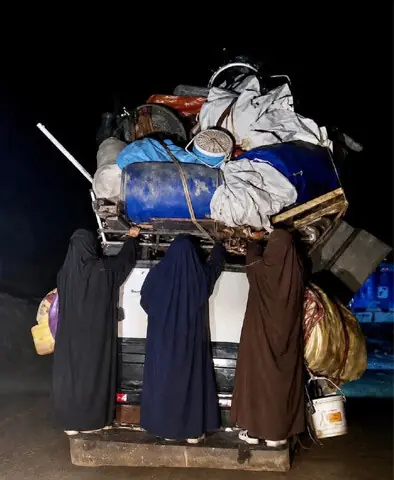Tribal women cling to a vehicle carrying their luggage while leaving Dattakhel tehsil of North Waziristan. — Dawn