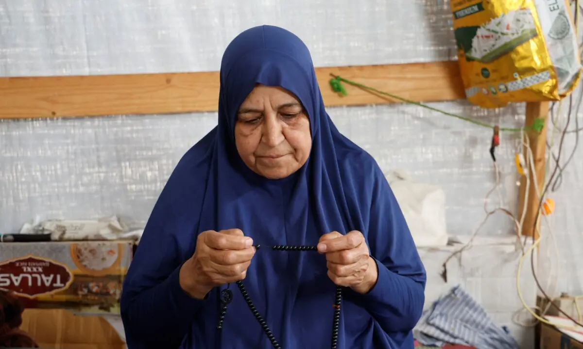 Palestinian Najia Abu Lehia sits inside a tent at a camp for displaced people, holding prayer beads in her hand on May 18, 2026. —REUTERS