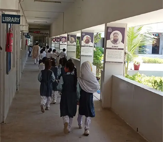 Children walking down the corridor of VM Public School lined with photos of successful alumni