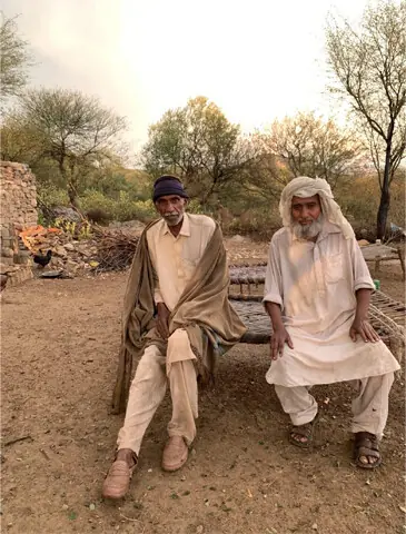 Mohammad Haneef (left) and Mohammad Rafique (right) sit on a charpoy in their courtyard.
