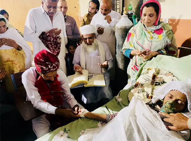 Advocate Sardar Faiz holds the hand of his unconscious mother, Robina Bibi, as a cleric solemnises his nikah in the pulmonology ward of a hospital in Muzaffarabad on Thursday night. Robina Bibi, who had been battling cancer for nearly three years, passed away only hours later after witnessing the fulfilment of her final wish. — Photo by the writer