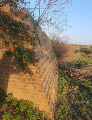 The stone fortifications surrounding the water pond and its staircase are slowly disappearing under the weight of neglect.
